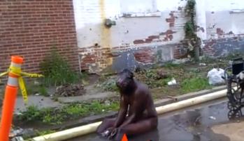 Hombre bañándose con lodo y agua sucia contaminada en plena calle 